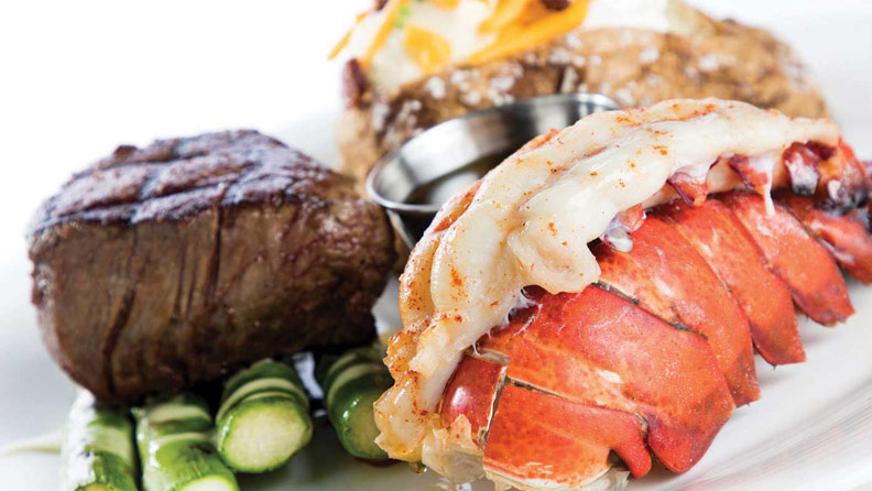 steak and lobster with a baked potato and asparagus